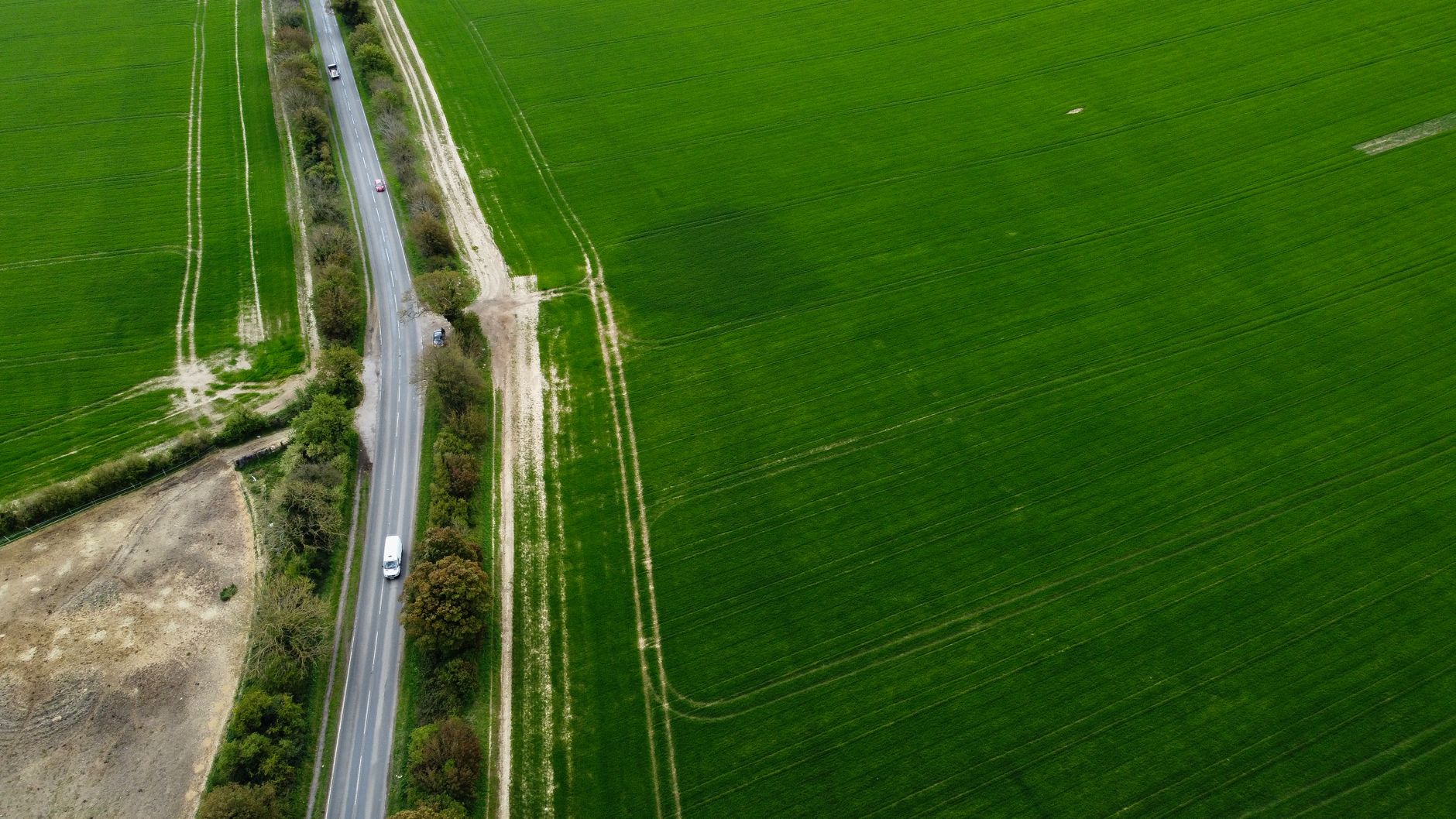 Luftfoto af en landevej mellem grønne marker